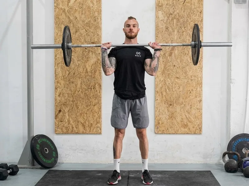 Push Press phối hợp lực chân và vai để đẩy thanh qua đầu